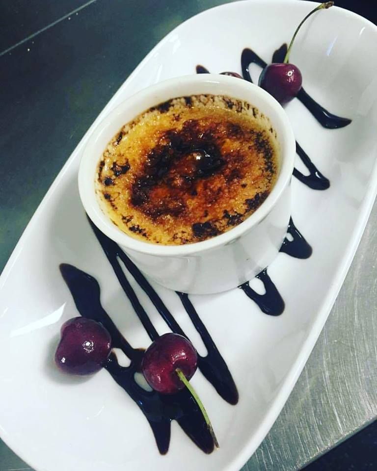 A crème brûlée with fresh cherries