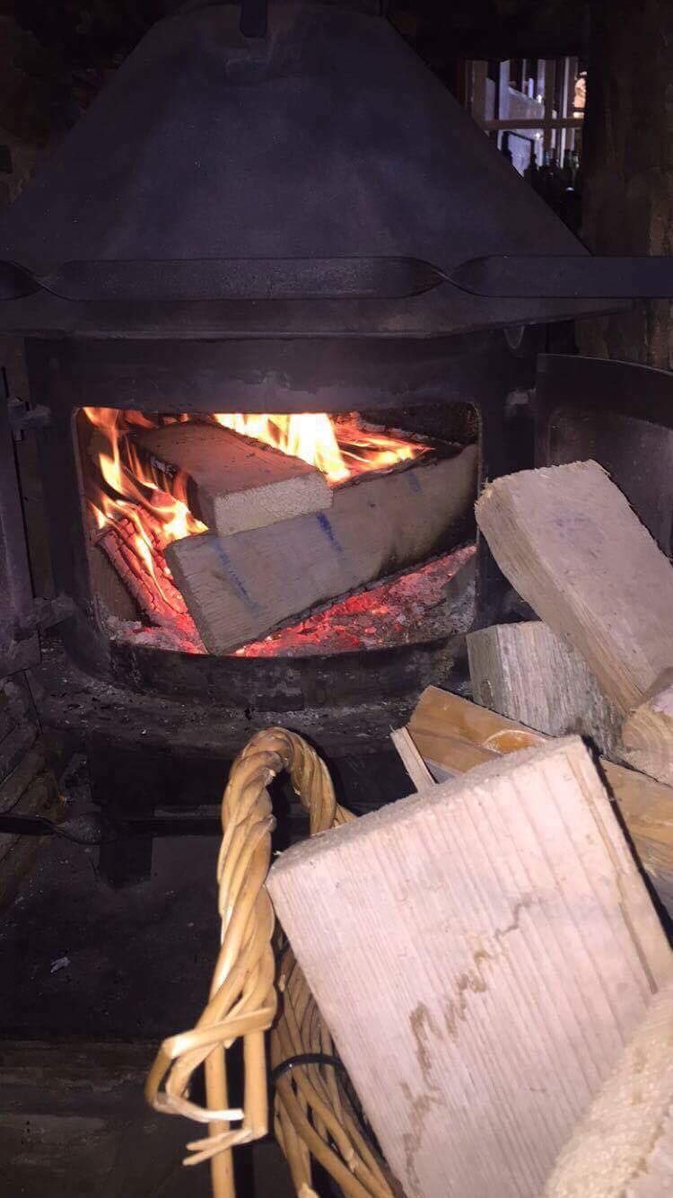 A log burner lit, with logs stacked beside it