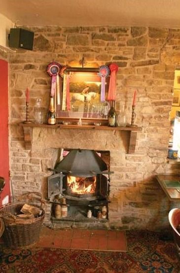A fireside corner with a stone chimney breast and a rug
